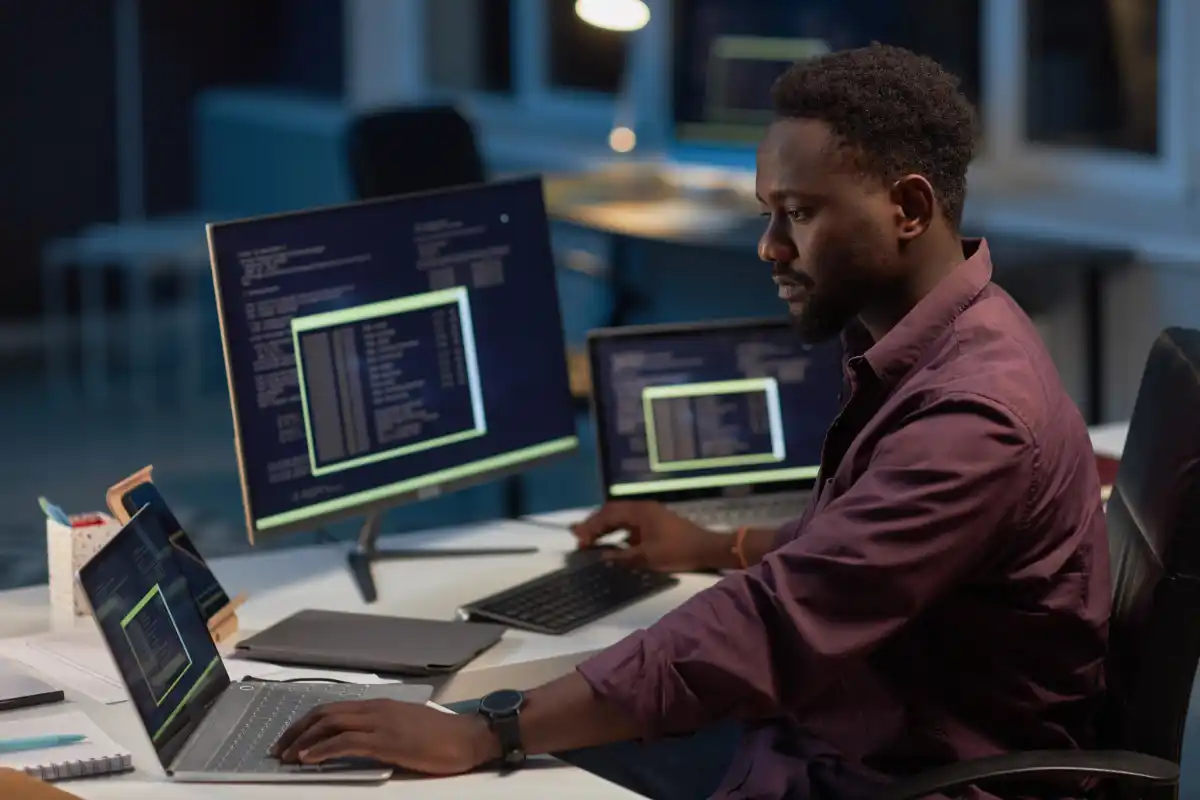 IT specialist working across two laptops backing up data